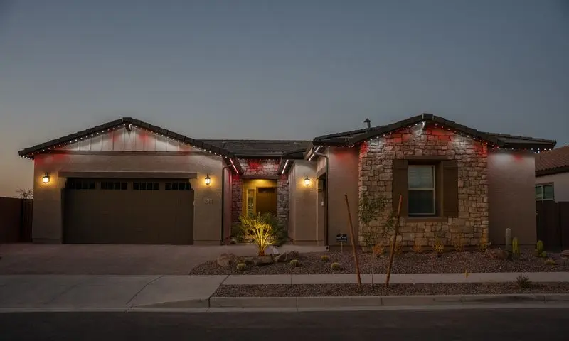 Single-story desert home at twilight with alternating red and warm white permanent roofline lighting