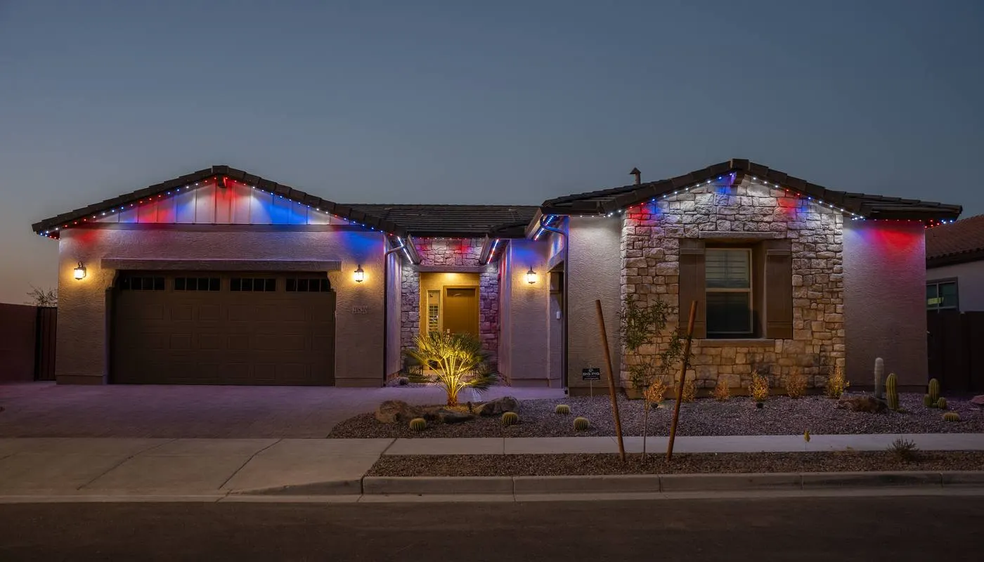Desert home at dusk with red, white, and blue permanent roofline lighting for Independence Day